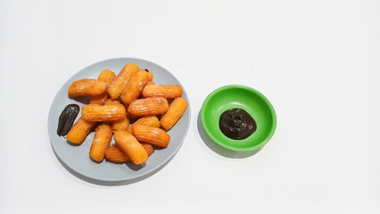 Churros sticks in a small plate with white powdered sugar and a bowl of chocolate sauce