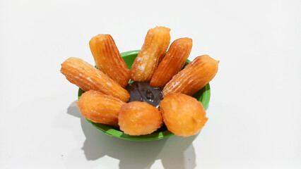 Churros sticks in a small plate with white powdered sugar and a bowl of chocolate sauce