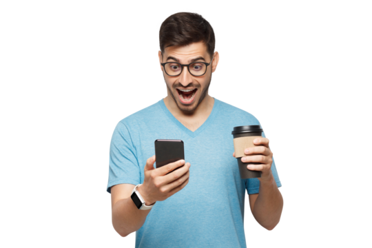 Portrait of young handsome man in blue t-shirt and glasses, with cup of coffee, looking at phone screen with shocked face