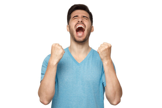 Young man shouting with closed eyes, celebrating victory, squeezing fists in deep emotional expression of happiness and luck