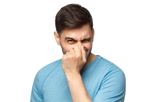 Young man holding his nose as smelling something rotten and stinky, trying to find source of odor