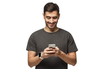 Young man standing, looking at screen of phone with smile, browsing web pages or chatting with friend