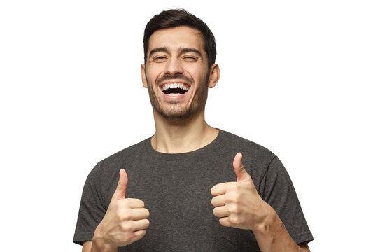 Excited smiling young man making thumbs up gesture of approval and success
