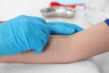 Nurse inputting catheter for IV drip in patient hand, closeup