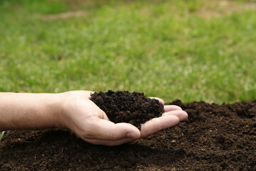Woman holding pile of soil outdoors, closeup. Space for text