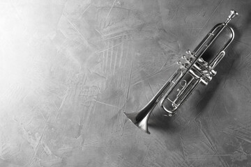 Shiny trumpet on grey textured table, top view. Space for text. Wind musical instrument