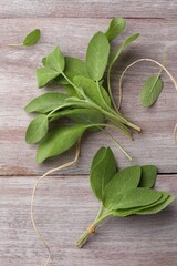 Green sage leaves on color wooden table, flat lay