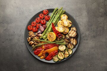 Delicious grilled vegetables on grey textured table, top view