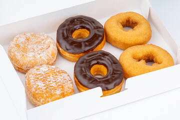 Donut or Doughnut. Donuts or Doughnuts box with chocolate brown glazed cream or icing without sprinkles. Dessert on birthday, holiday party. Advertising coffee shop, bakery, cafe. American style Donut