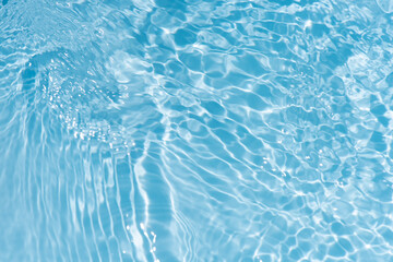 Obraz premium Blue water with ripples on the surface. Defocus blurred transparent blue colored clear calm water surface texture with splashes and bubbles. Water waves with shining pattern texture background.