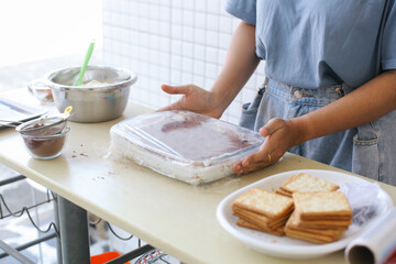 Woman Hands Putting Tiramisu Cake Inside Closed Bowl On Kitchen Table