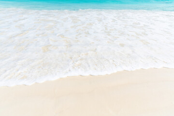 Soft, white wave gently laps onto the sandy beach, creating a calming and peaceful scene. Abstract tropical nature backgrounds