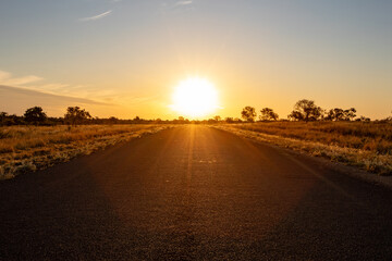 Low angle view of a deserted old paved road bathed in the warm glow of a setting sun.