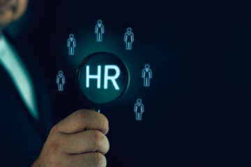 Businessman use the magnifying glass to find human icon for human development recruitment concept. New job, searching for a new team member. Job opportunity hiring concept