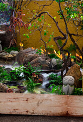 Minimal Japanese garden in home with small stone lantern and bamboo fountain and moss and flowers.
