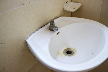 A close-up image of a white bathroom sink with a chrome faucet. The sink is empty, and the faucet is turned off. Close up of a White Bathroom Sink Background.