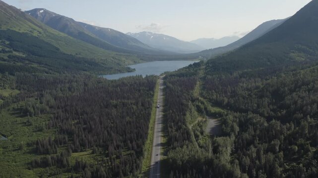 Panoramic view of cars traveling along Seward Highway with scenic lake and mountain landscape on Kenai Peninsula near Seward, Alaska - 4K Drone