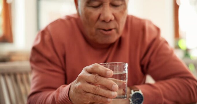 Drinking water, senior man and Parkinson or tremor with trembling hands at table in living room. Sick, elderly person and glass with neurology, muscle or shaking illness in lounge of retirement home
