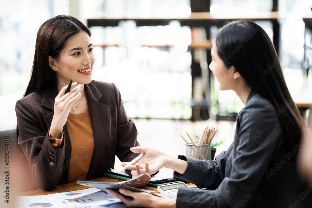 Wall mural two young asian business woman talking, consulting and discussing working with new startup project i