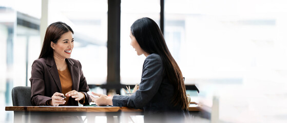 Two young Asian business woman talking, consulting and discussing working with new startup project...