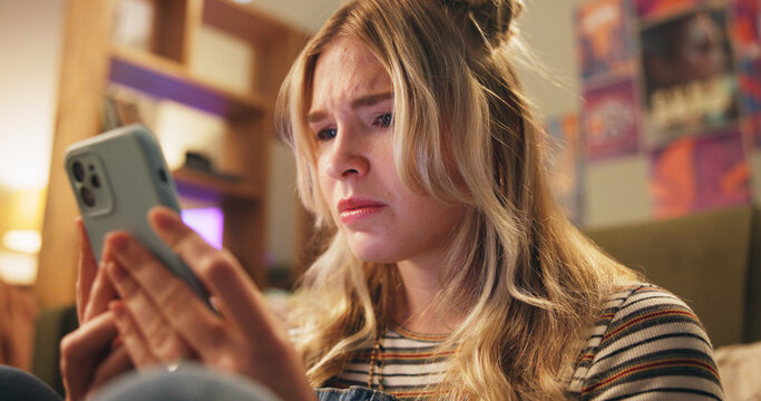 Sad, online and girl with phone in bedroom depressed for bad news, cyber bully and breakup chat. Communication, home and person on smartphone for social media, website and internet for rude text