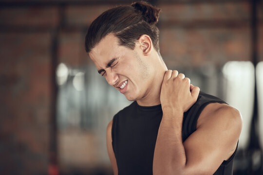 Frustrated man, fitness and neck pain with muscle tension from injury, accident or inflammation at gym. Male person with sore spine, joint or sprain in discomfort from workout or indoor exercise