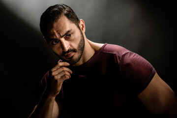 Portrait of strong handsome man with brutal unshaven face posing on dark background, Dark allure:...