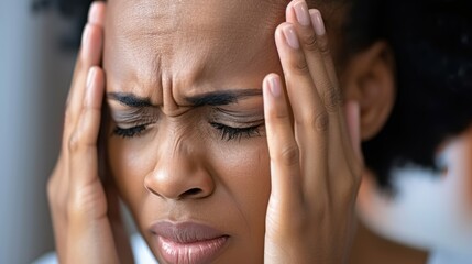 Fototapeta premium Afro woman enduring a severe headache. Her eyes closed and brow furrowed, fingertips gently pressing against her temples, gesture of pain and discomfort.