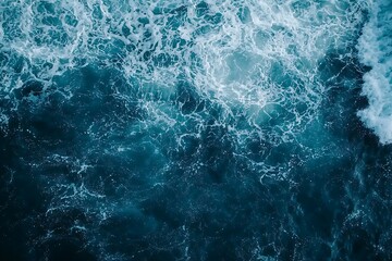Fototapeta premium Aerial view of dark blue ocean water with white foam.