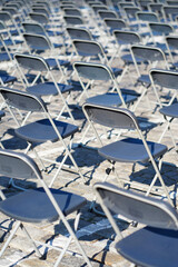 Many empty plastic gray chairs prepared for an event on a cobblestone square