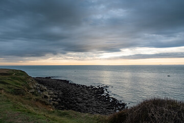 Serene coastal scene featuring calm ocean waters under a cloudy sky during sunset, perfect for relaxation.