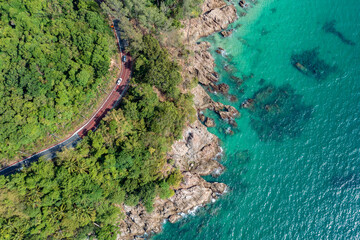 Aerial view of two cars on the road running along the rocky coastline