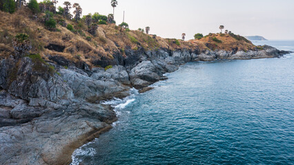 Rocky coastline cliffs, sea water surface aerial view, Promthep cape, Phuket, Thailand.