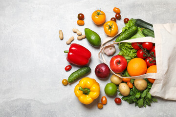 Vegan food delivery. Bag with different fresh vegetables, nuts and fruits on grey textured table, flat lay. Space for text