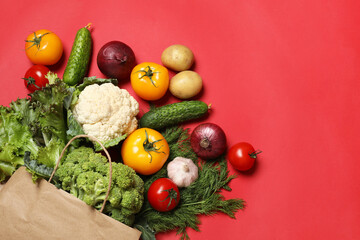 Delivery of vegetarian products. Bag with different vegetables on red background, top view. Space for text