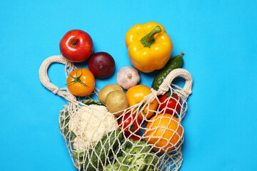Delivery of vegetarian products. Bag with different vegetables and fruits on light blue background, top view