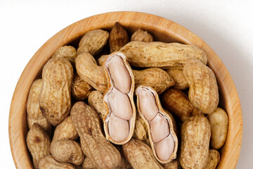 Wooden bowl filled with boiled peanuts (Arachis hypogaea), perfect as a snack, photographed against a white background.