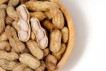 Wooden bowl filled with boiled peanuts (Arachis hypogaea), perfect as a snack, photographed against a white background.