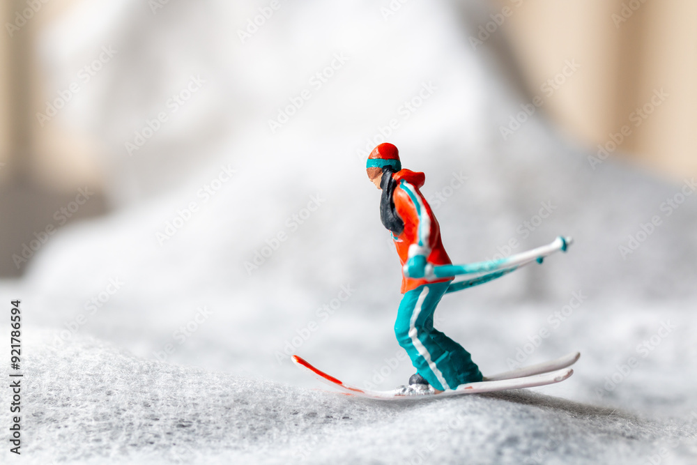 Wall mural Miniature figurine of a skier in motion skiing across a white snowy landscape