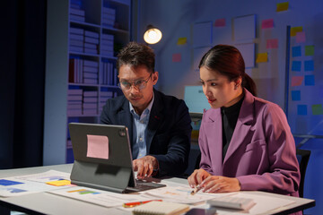Two Asian businesspeople discuss the working information of a financial investment project. Marketing and growth strategies and company revenue calculations Save data to a laptop in the office.