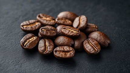 Naklejka premium A pile of coffee beans on a dark surface. The beans are of different sizes and are spread out