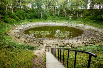Kaali meteorite crater on Saaremaa island in 2024. Round lake in summer, surrounded with trees....