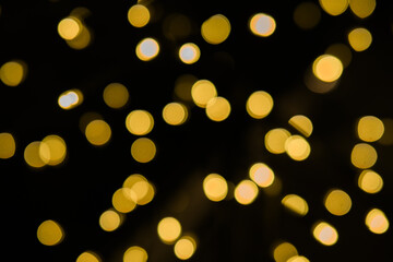 Beautiful glowing golden bokeh lights on a dark black background, perfect for festive occasions like christmas or new year's eve