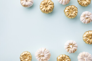 Stylized white and gold decorative pumpkins on a pale blue background for autumn and Thanksgiving cards.