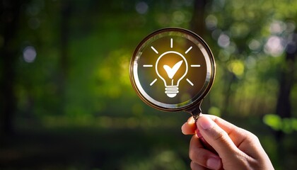 A hand holding a magnifying glass with a light bulb icon inside, symbolizing the search for ideas and solutions
