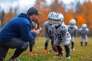 A football coach is instructing young players dressed in football gear during a practice session on the field, emphasizing training, guidance, and sportsmanship.