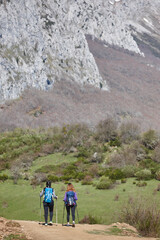 Obraz premium Two female backpacker hikers on a pathway. Mountain trekking