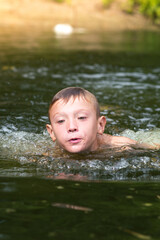 a boy bathes in a river in the summer on a hot day	
