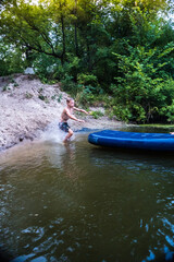 a boy bathes in a river in the summer on a hot day	