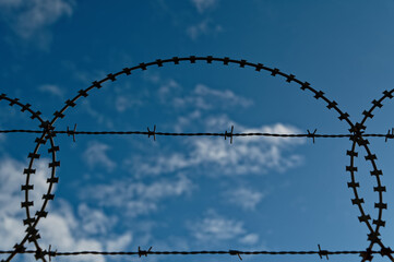 Razor and barbed wire against a blue sky.
